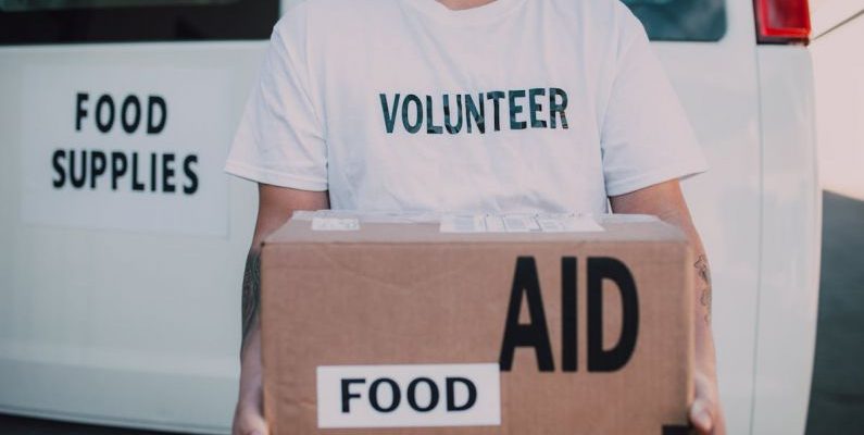 Volunteer Organizations - Volunteer Holding Box of Food Aid