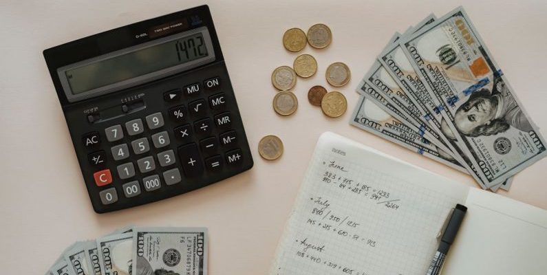Budgeting - Black Calculator beside Coins and Notebook